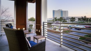 A balcony with wicker furniture and a view of a parking lot and buildings. - Bungalow Hotel (Long Branch)