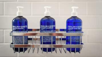 Uno scaffale in bagno con tre prodotti MALIN+GOETZ.