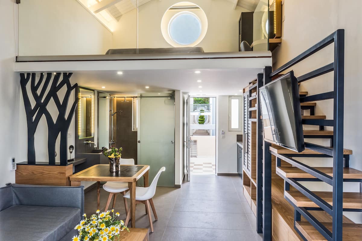 A modern interior with a dining area, a staircase, and a TV mounted on the wall.
