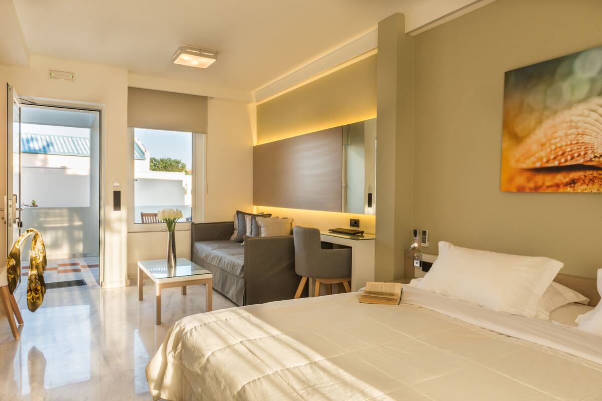 A modern hotel room with a large bed, a desk, and a comfortable seating area.
