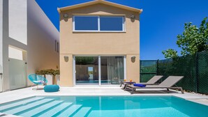 A modern two-story house with a swimming pool, a glass door entrance, and a fenced backyard.