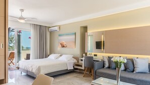 A modern hotel room with a bed, a sofa, a desk, and a glass coffee table.