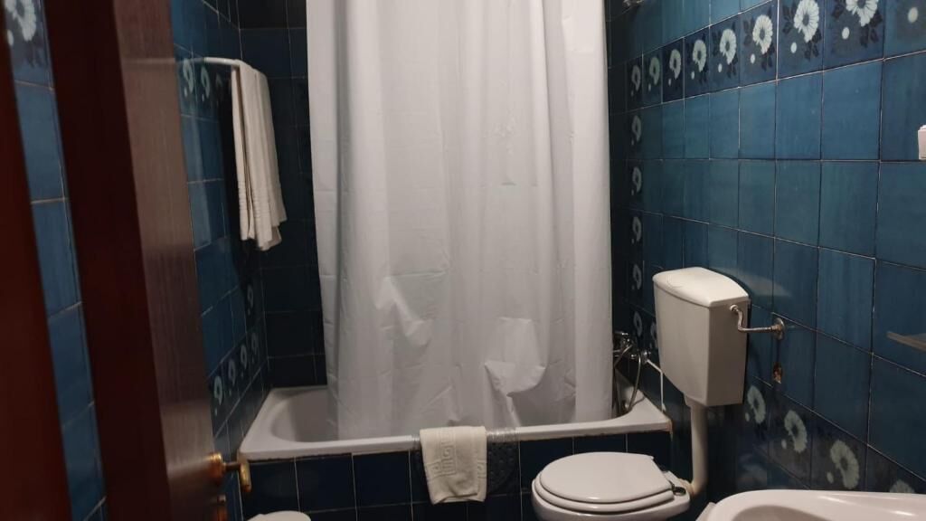 Un baño con bañera, inodoro y cortina de ducha.