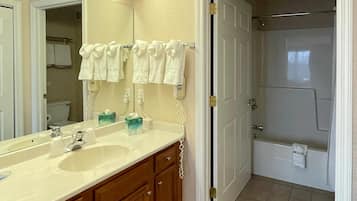 A bathroom with a double sink, a mirror, and a shower area.