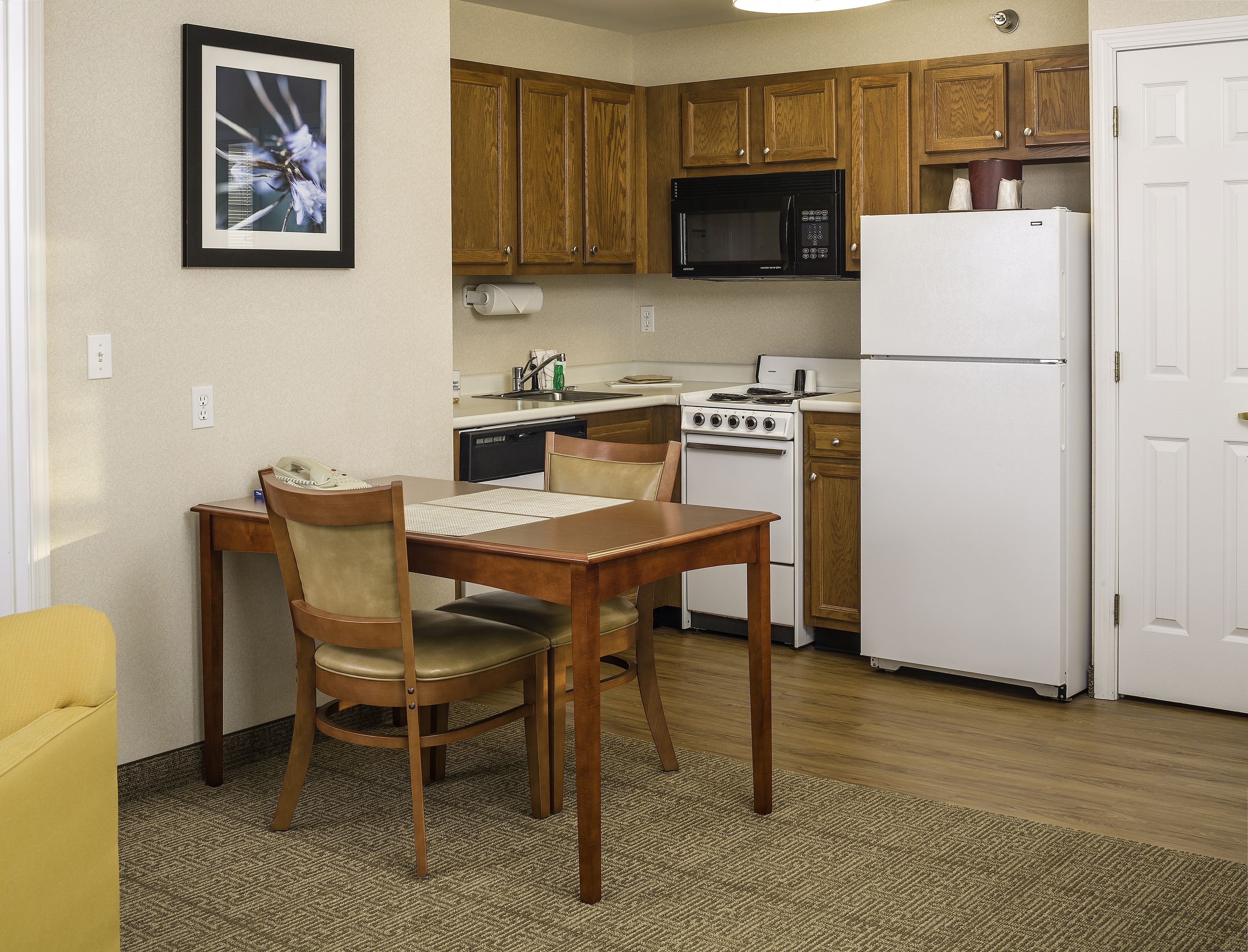 A compact kitchen with wooden cabinets, a microwave, a stove, and a refrigerator.
