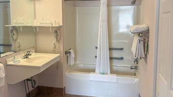 A bathroom with a bathtub, a sink, a mirror, and a towel rack.
