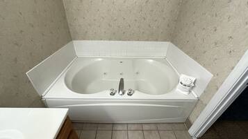 Une salle de bain d’angle avec une baignoire sur pieds, des carreaux blancs et un meuble en bois.