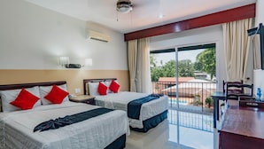 A hotel room with two beds, a desk, a chair, a balcony with a view, and a ceiling fan. - Hotel Siglo 21 Merida (Mérida)