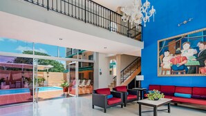 A spacious lobby with a pool, red sofas, and a large painting on the wall. - Hotel Siglo 21 Merida (Mérida)