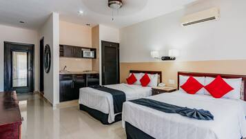 Habitación de hotel con dos camas, kitchenette, ventilador de techo y aire acondicionado.
