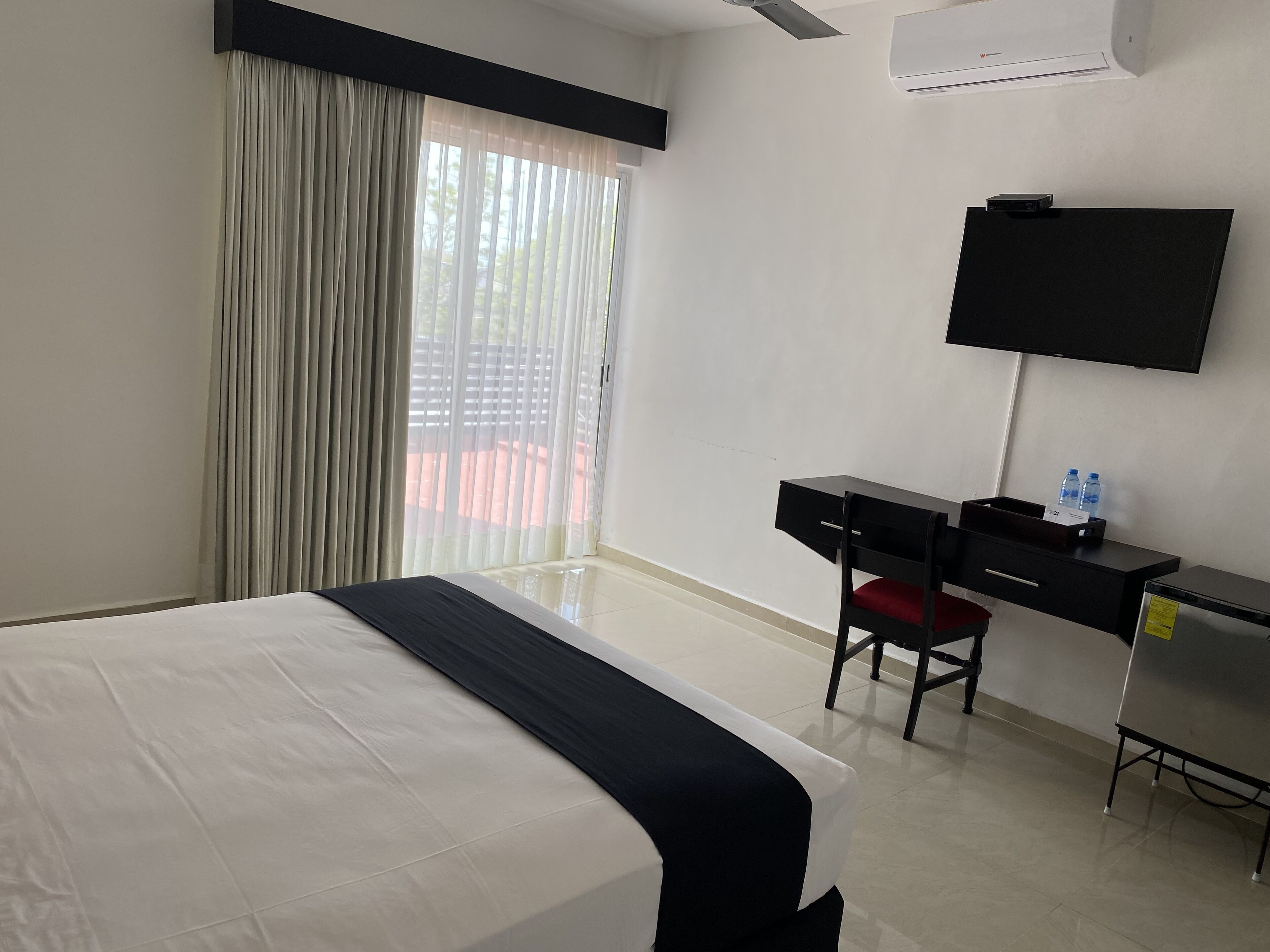 Ein Hotelzimmer mit Bett, Schreibtisch mit Stuhl, Fernseher und Klimaanlage.