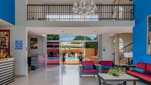 A spacious living area with a pool, red and blue furniture, a chandelier, and a staircase to a balcony. - Hotel Siglo 21 Merida (Mérida)