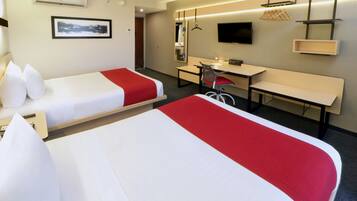 A hotel room with two beds, a desk, a chair, a TV, and a mirror.