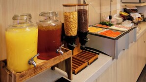Um buffet de café da manhã com diversas opções de alimentos e bebidas.