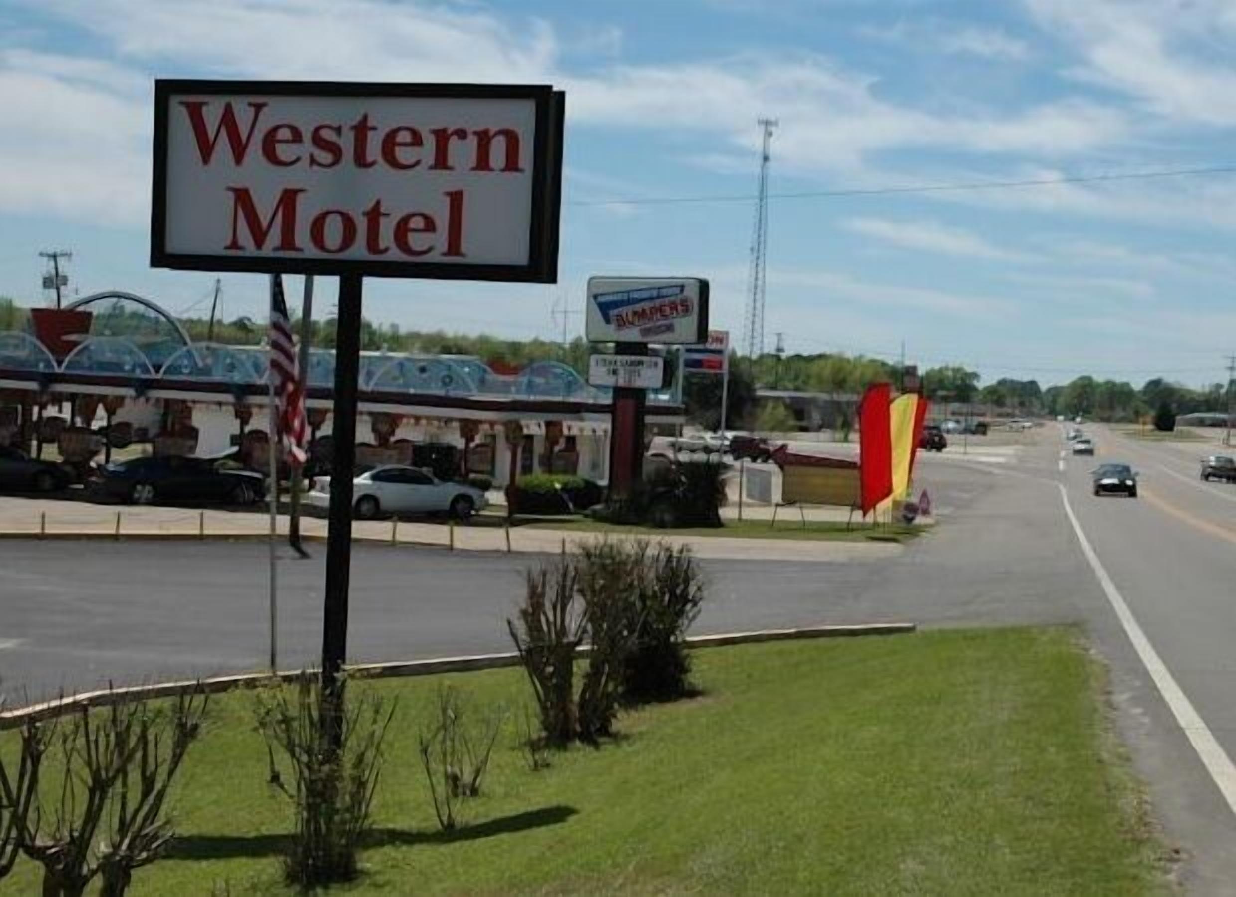 A Western Motel sign with a Burger King and a gas station in the background.
