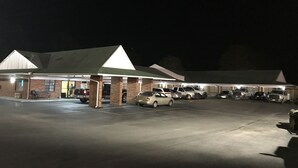 A building with a covered parking area and multiple vehicles parked. - Western Motel - Prentiss (Prentiss)