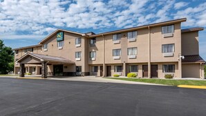 A multi-story hotel with a flat roof, a covered entrance, and a parking lot.