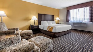 A hotel room with a large bed, two bedside tables, a chair, and a window with curtains.