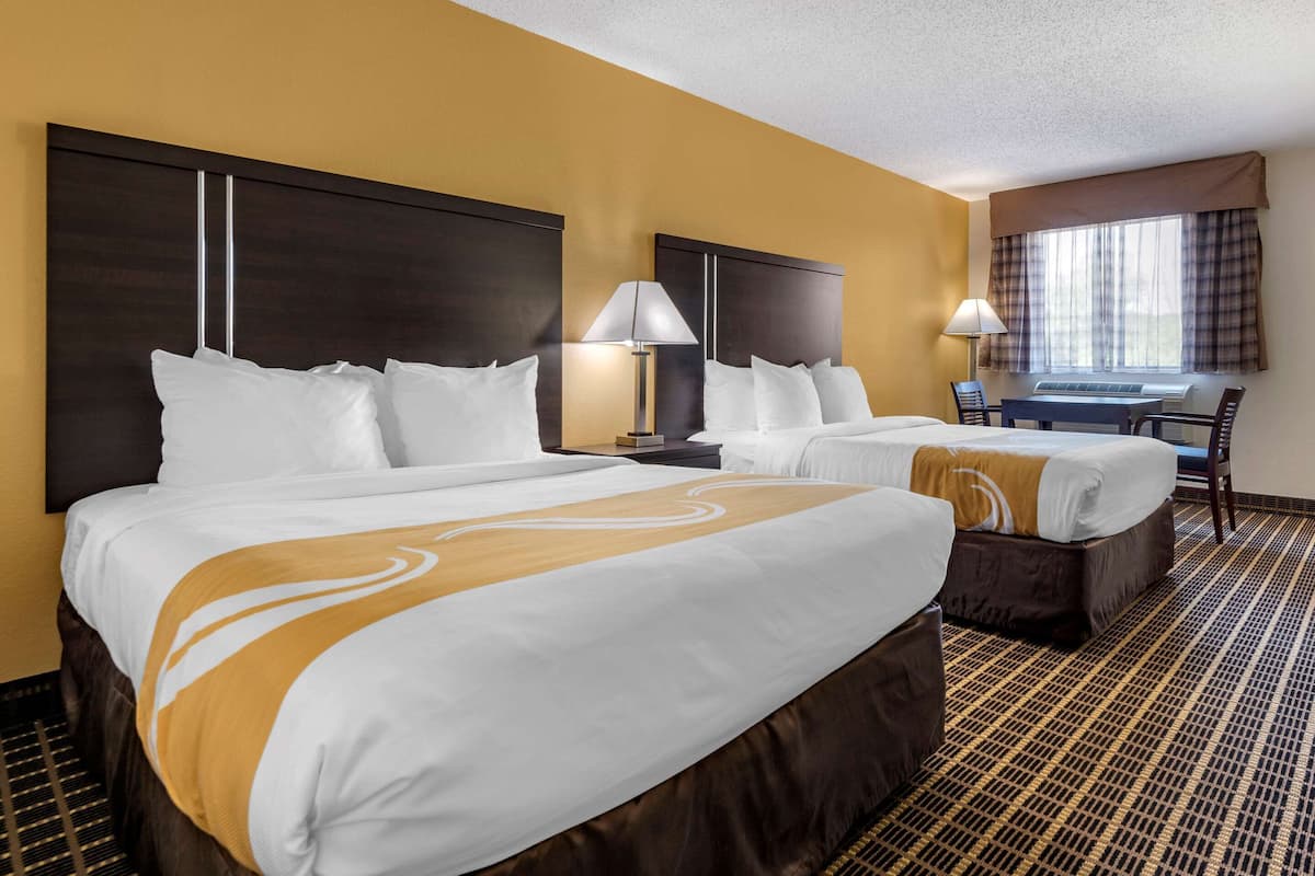 Ein Hotelzimmer mit zwei Betten, einem Schreibtisch und einem Stuhl.