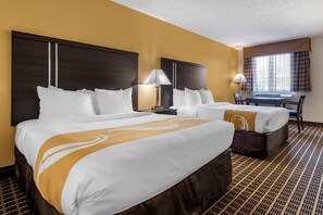A hotel room with two beds, a desk, and a chair.