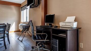 A modern office space with a desk, chair, computer, printer, and a TV mounted on the wall.