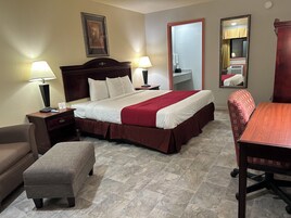Quarto de hotel com cama, duas mesas de cabeceira com luminárias, uma cadeira, uma mesinha e um espelho.