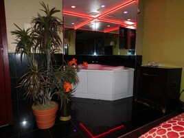 Un baño moderno con un espejo grande, una bañera blanca y una planta en maceta.