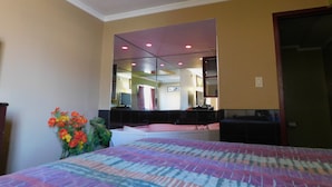 A hotel room with a bed, a large mirror, and a small plant. - Mounts Motel (Lawrenceville)