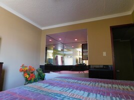 Una habitación de hotel con cama, un espejo grande y una planta pequeña.