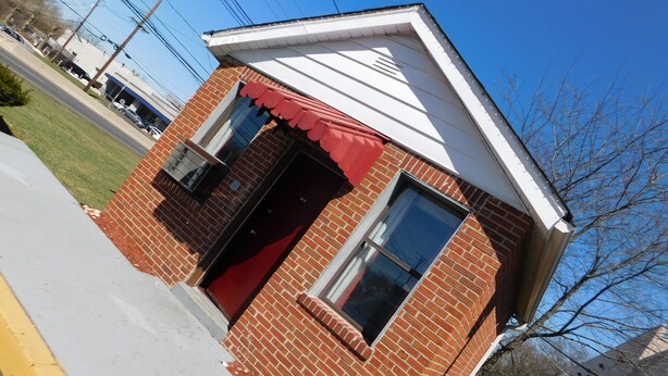A small brick building with a red awning and a single visible window. - Mounts Motel (Lawrenceville)