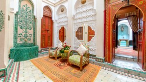 A traditional interior with ornate arches, a patterned rug, and a seating area with cushions and a vase of flowers. - Riad Hikaya (Marrakech)