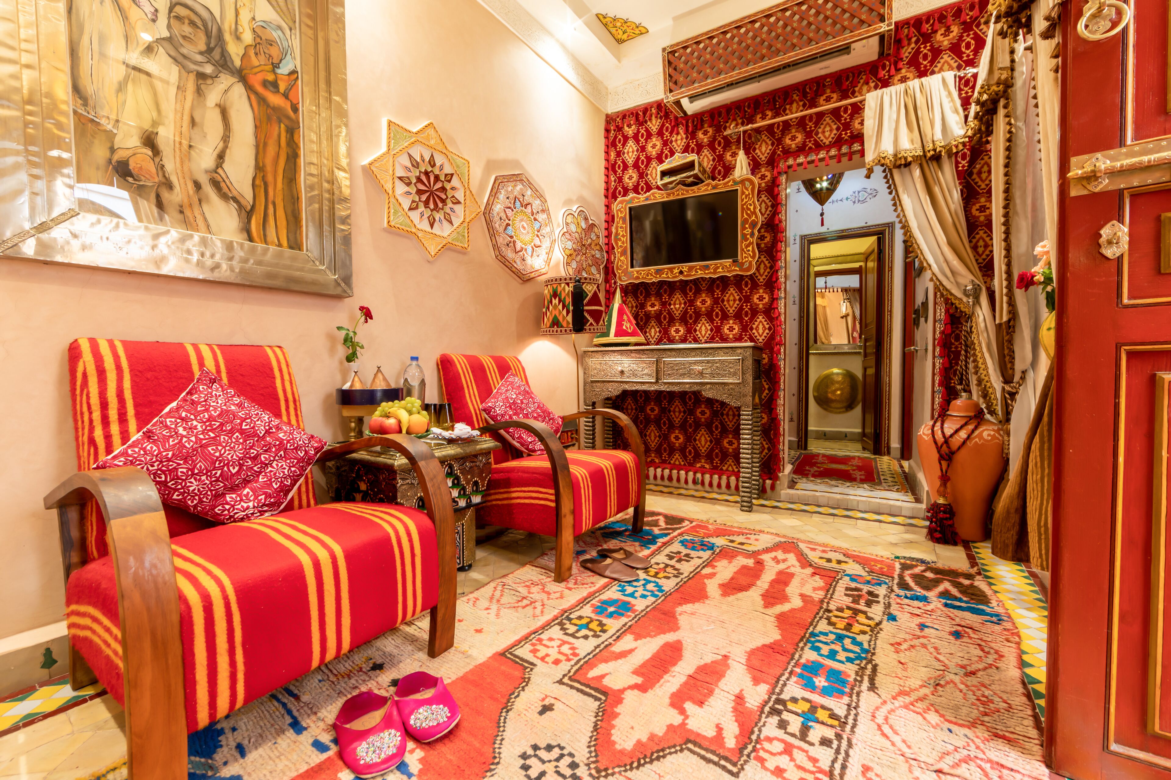 Una habitación tradicional marroquí con un sofá, un armario de madera y una alfombra estampada.