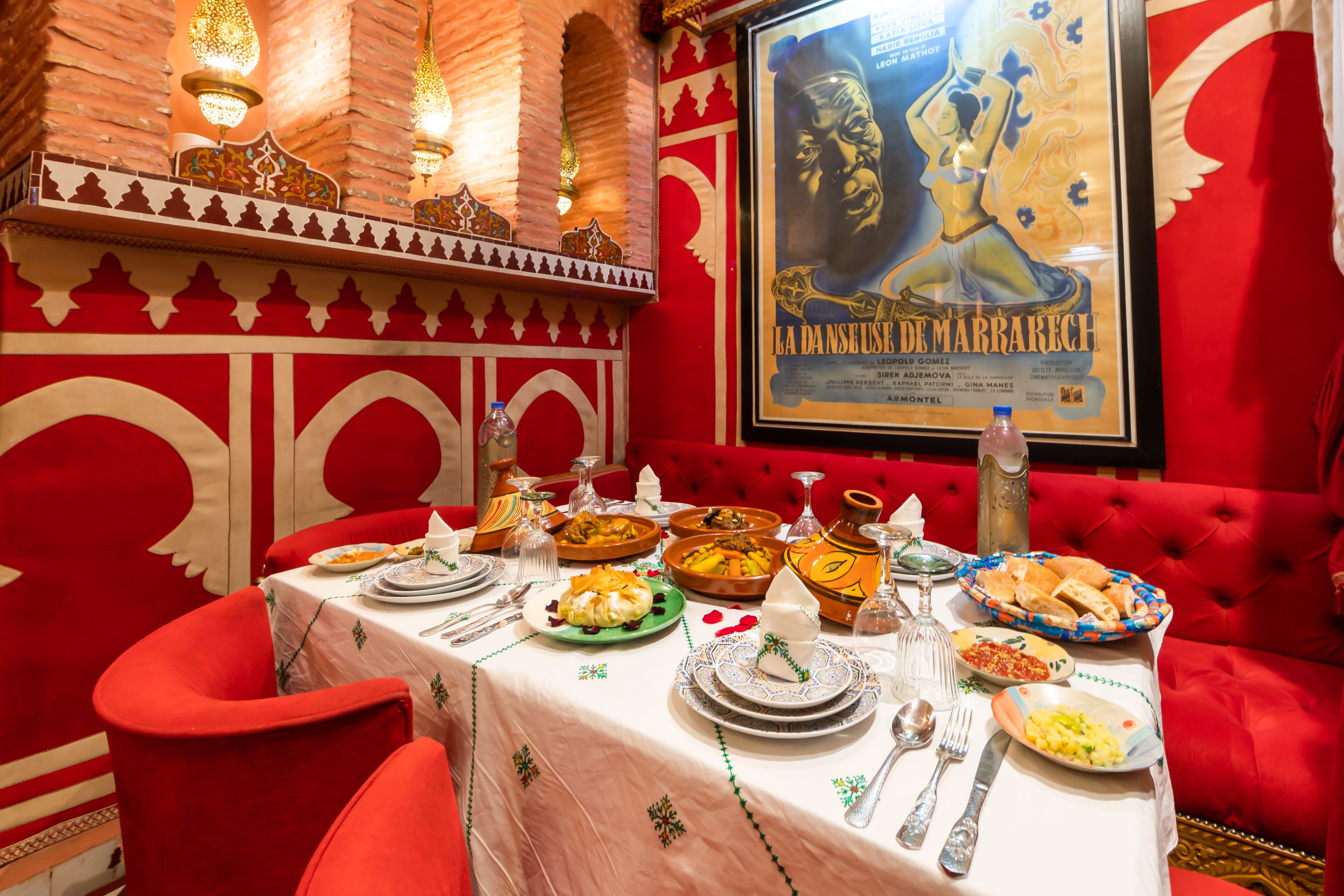 A dining table set with various dishes, a poster on the wall, and a red upholstered sofa.