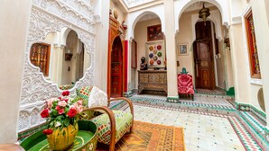 An interior courtyard with ornate arches, a seating area with cushions, and a decorative wall. - Riad Hikaya (Marrakech)