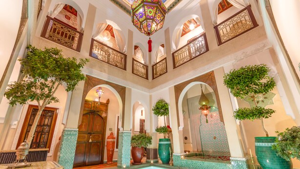 A luxurious indoor pool area with ornate arches, decorative lighting, and potted plants. - Riad Hikaya (Marrakech)