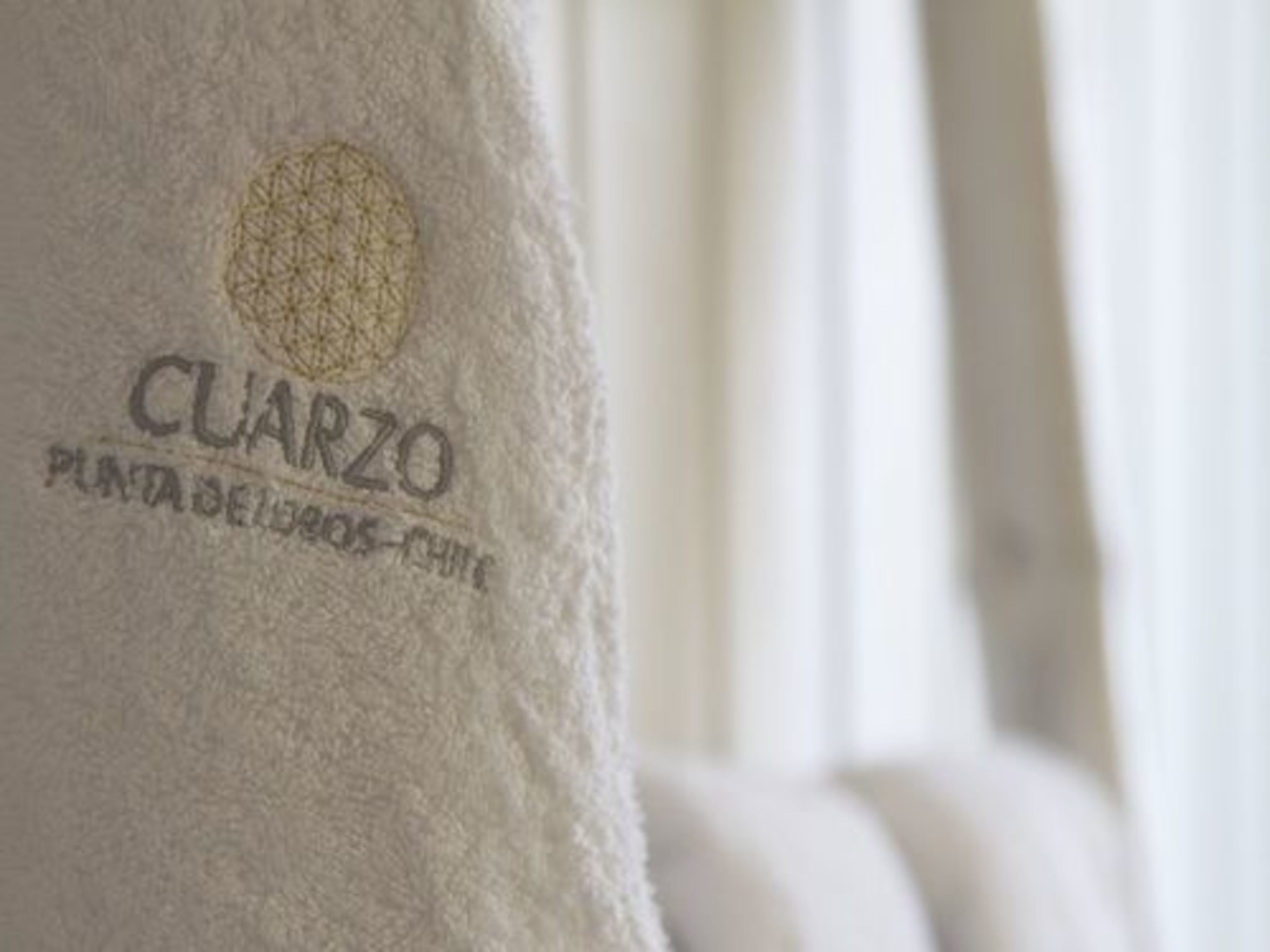 A white towel with embroidered text "CUARZO" and "PLANTA DE LOBOS - CHILE".