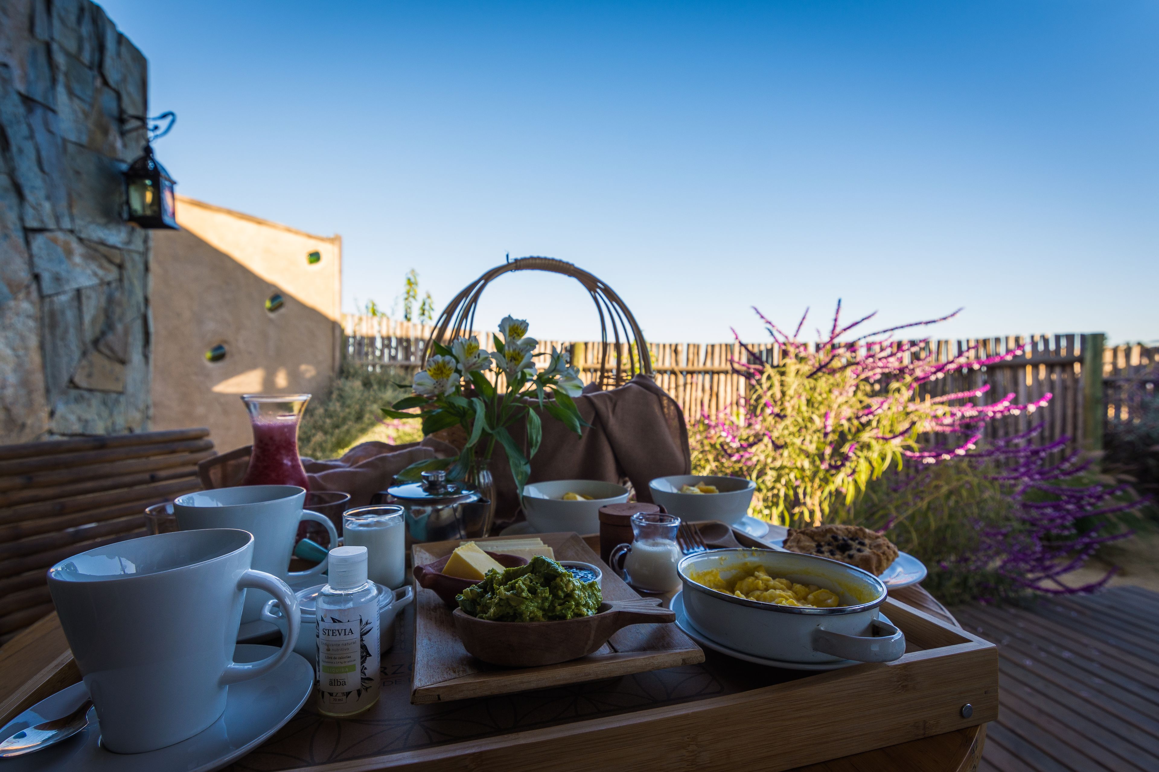 Une table en bois, dressée pour le petit-déjeuner, avec des tasses, des bols et un plateau.