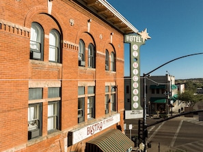Un hotel histórico con un letrero llamativo, ventanas en arco y un toldo antiguo.