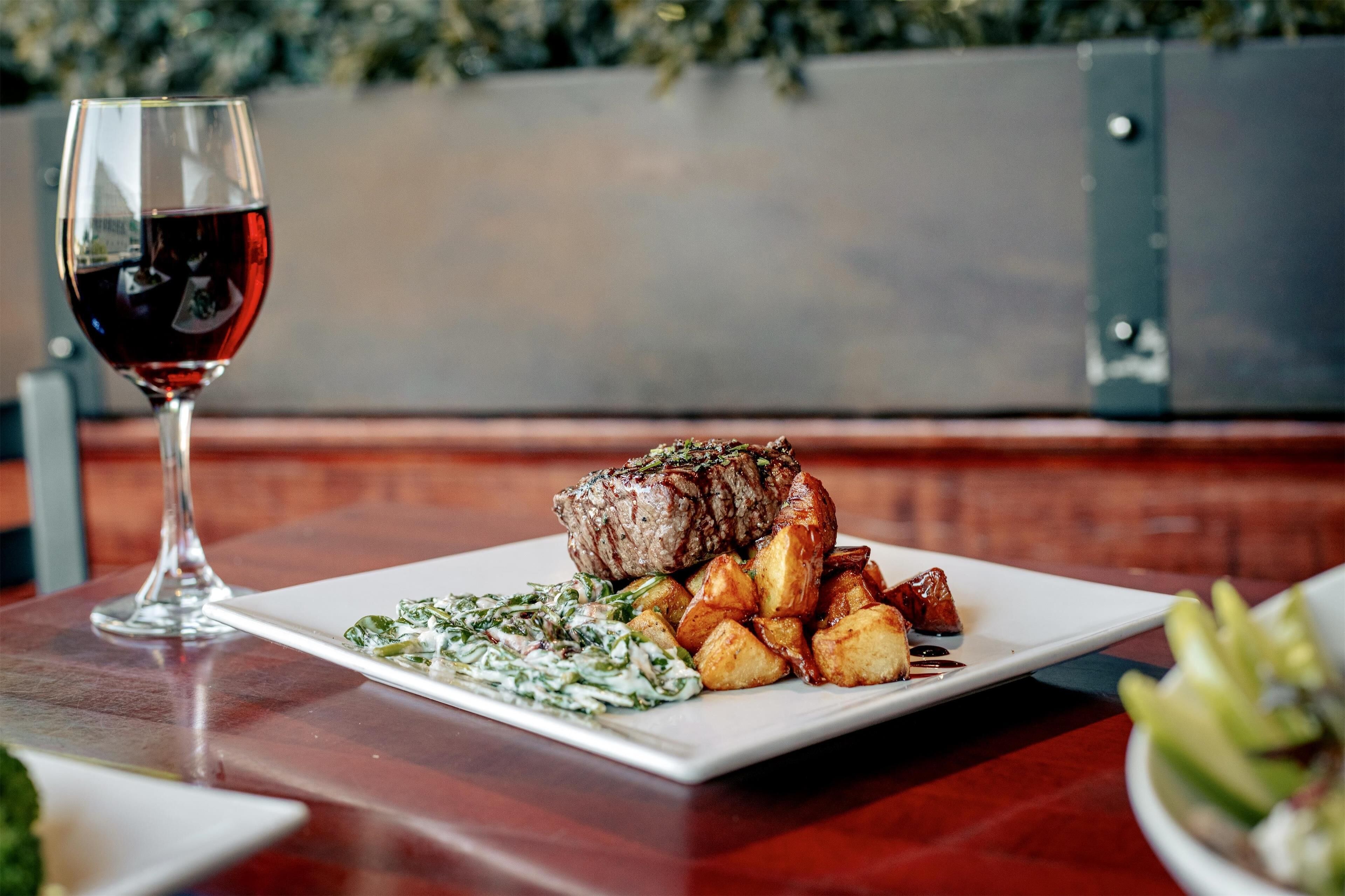 A plate of food with a glass of red wine on a wooden table.