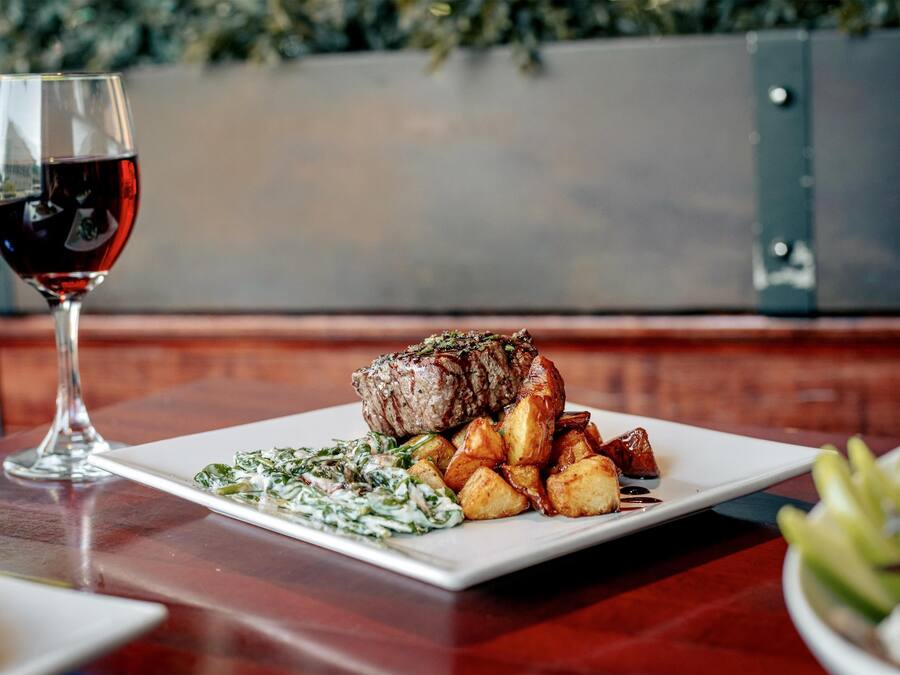A plate of food with a glass of red wine on a wooden table.