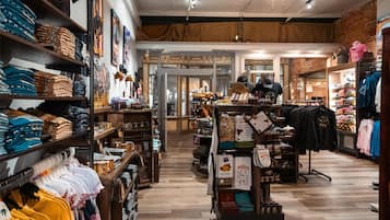 A clothing store with shelves of folded clothes, racks of hanging shirts, and a display of accessories.