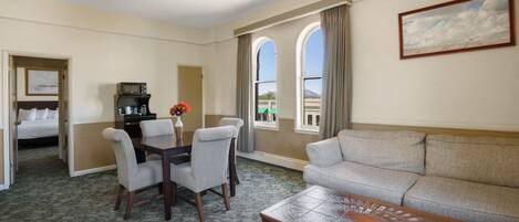 A hotel room with a dining area, a sofa, a coffee table, and a ceiling fan.