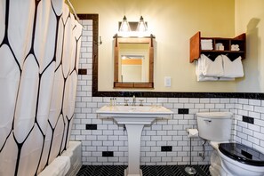 Une salle de bain avec un lavabo blanc, des murs carrelés en noir et blanc, des toilettes et un porte-serviettes.