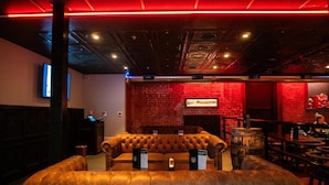 A cozy lounge area with a leather couch, wooden tables, and a brick wall backdrop. - Hotel St. Michael, BW Premier Collection (Prescott)