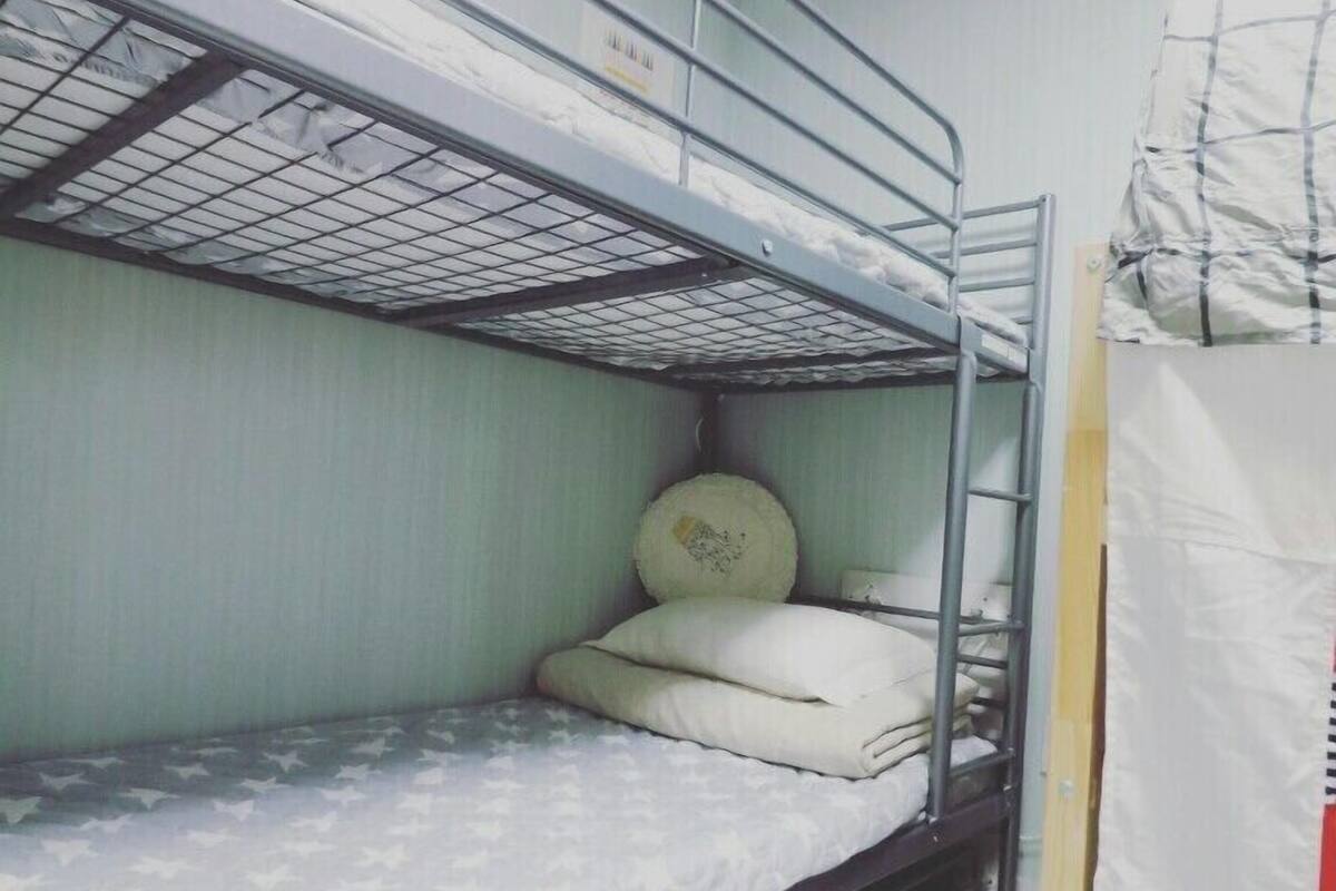 A bunk bed room with a metal frame, a pillow, and a sun decoration on the ceiling.
