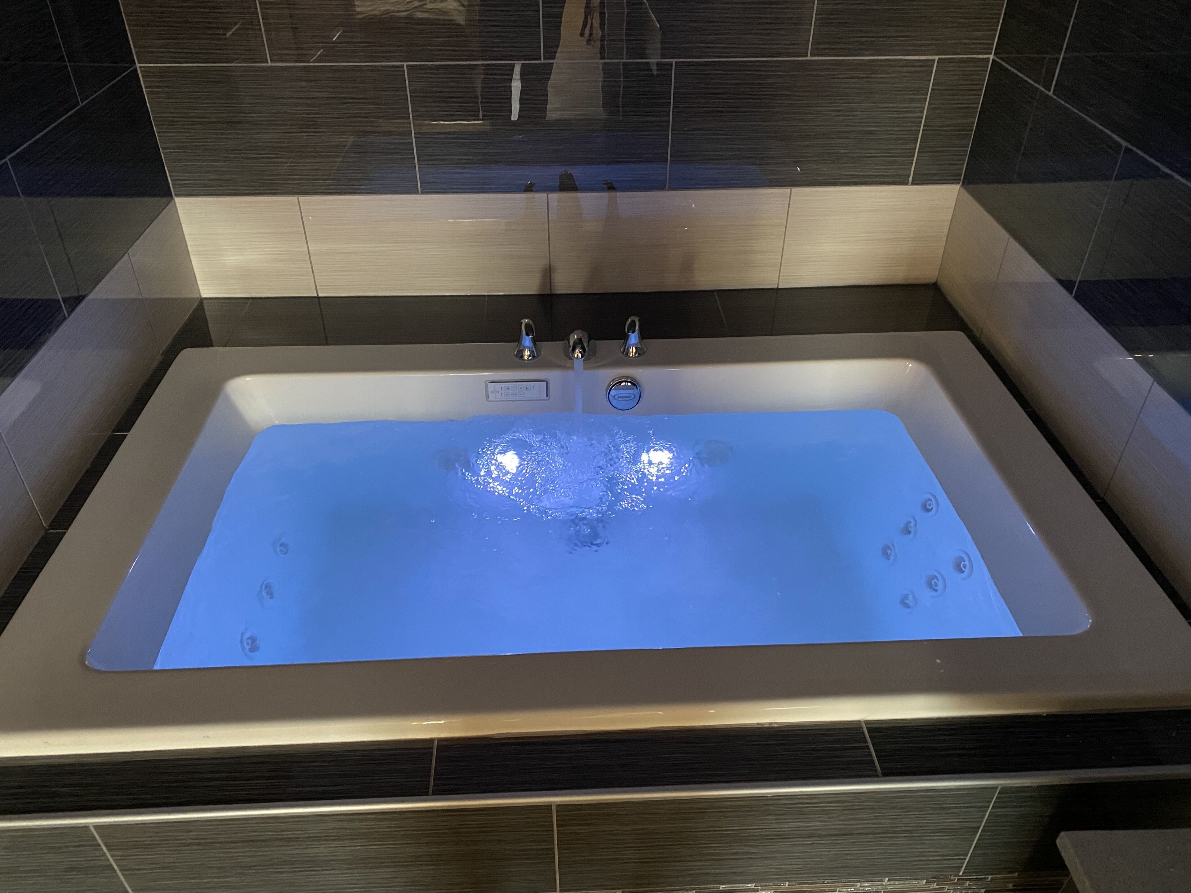 A rectangular bathtub with a smooth, reflective surface and a single faucet.
