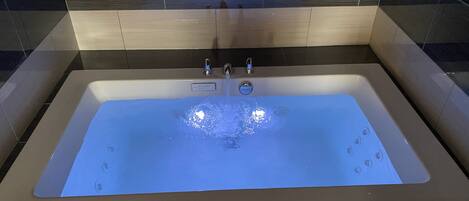 A rectangular bathtub with a smooth, reflective surface and a single faucet.