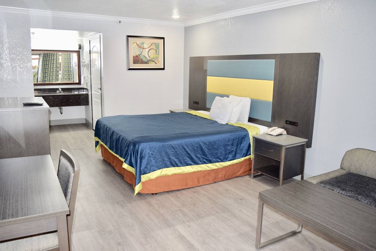 A hotel room with a bed, desk, chair, and a small table.