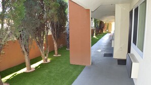 A corridor with artificial grass, trees, and a building facade. - Budget Inn La Puente (La Puente)