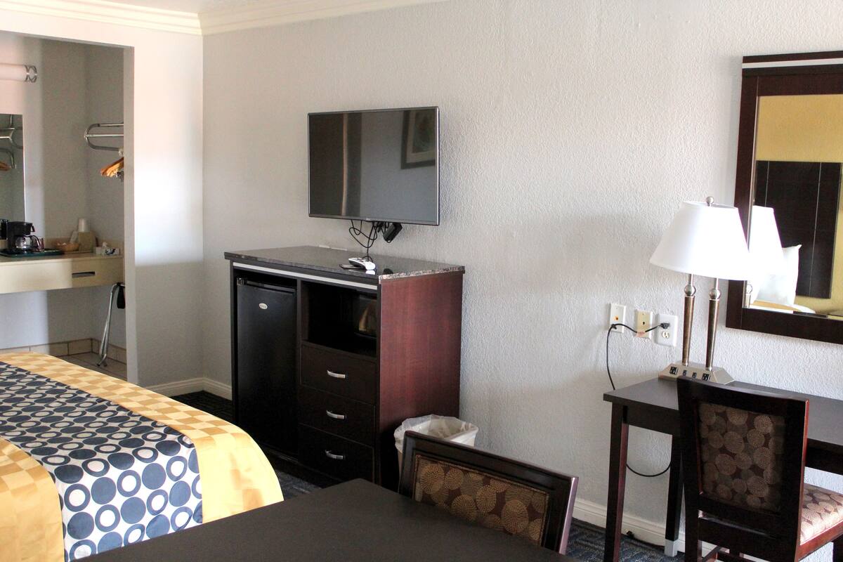 Een hotelkamer met een bed, een bureau, een televisie, een lamp en een spiegel.